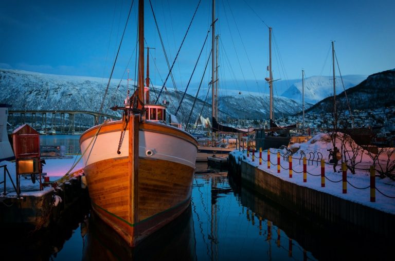 Norwegen Fjord mit Segelboot (Bootsführerschein) und schneebedeckten Bergen im Hintergrund